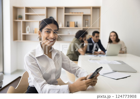 Indian woman sitting at desk in office with smartphone 124773908