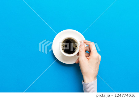 Minimalistic style woman hand holding a cup of coffee on Colored background. Flat lay, top view espresso cup. Empty place for text, copy space. Coffee addiction. Top view, flat lay Minimalistic style woman hand holding a cup of coffee on Colored background. Flat lay, top view espresso cup. Empty place for text, copy space. Coffee addiction. Top view, flat lay 124774016