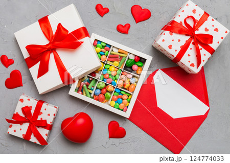 Red envelope with candy and gift box and Valentines hearts on colored background. Flat lay, top view. Romantic love letter for Holiday concept 124774033