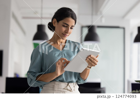 Serious Hispanic executive woman using business application on tablet Serious Hispanic executive woman using business application on tablet 124774093