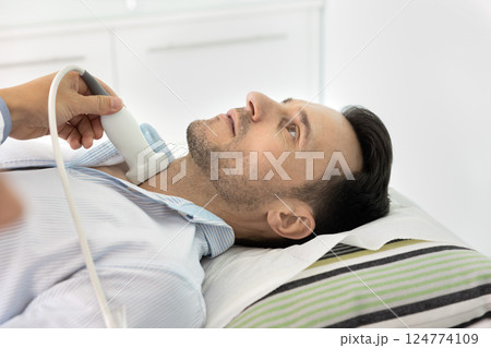 Man lying on examination table during ultrasound scanning procedure. Man lying on examination table during ultrasound scanning procedure. 124774109
