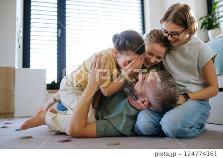Portrait of father with three daughters at home. 124774161