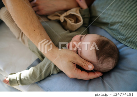Father putting the baby to sleep, lying next to him in the crib. 124774181