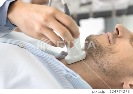 Closeup shot of male undergoing thyroid ultrasound examination in clinic Closeup shot of male undergoing thyroid ultrasound examination in clinic 124774278