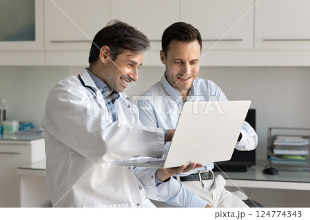Doctor and patient reviewing test results look at laptop screen 124774343