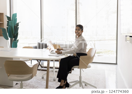 Young Indian woman working on laptop in modern office environment Young Indian woman working on laptop in modern office environment 124774360