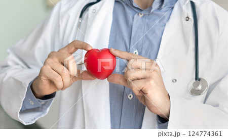 Man cardiologist holds small red heart, closeup 124774361