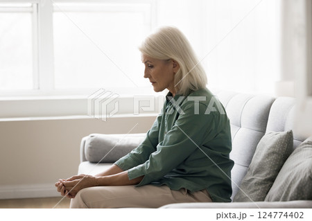 Sad older woman sit alone on couch suffer of depression 124774402
