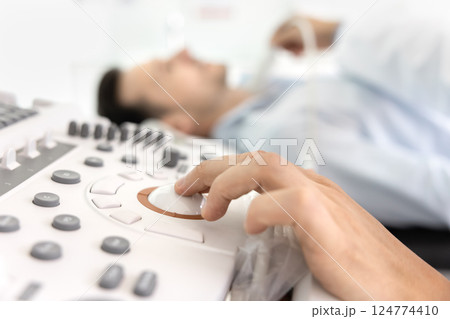 Doctor performs diagnostic scan adjusting controls on ultrasound machine Doctor performs diagnostic scan adjusting controls on ultrasound machine 124774410