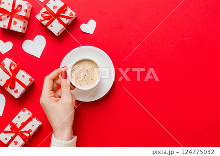 Flat lay of heart shaped cup of black coffee in the hands of women on colored background with copy space top view. Valentine day and holiday concept 124775032