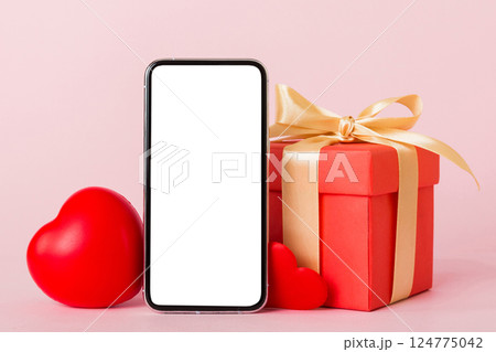 mobile phone with blank screen on colored background with hearts, calendar and gift box, valentine day concept perspertive view flat lay mobile phone with blank screen on colored background with hearts, calendar and gift box, valentine day concept perspertive view flat lay 124775042