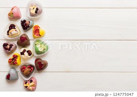 chocolate sweets in the form of a heart with fruits and nuts on a colored background. top view with space for text, holiday concept 124775047