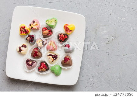Plate with different chocolate on colored background. Assortment of fine chocolates top view vith copy space Health and obesity concept 124775050