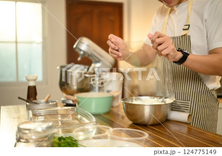 Man covering a mixing bowl of whipped cream with plastic wrap, ready for refrigeration 124775149
