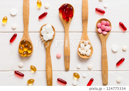 Vitamin capsules in a spoon on a colored background. Pills served as a healthy meal. Red soft gel vitamin supplement capsules on spoon Vitamin capsules in a spoon on a colored background. Pills served as a healthy meal. Red soft gel vitamin supplement capsules on spoon 124775334