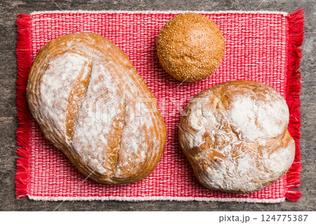 Assortment of freshly baked bread with napkin on rustic table top view. Healthy unleavened bread. French bread Assortment of freshly baked bread with napkin on rustic table top view. Healthy unleavened bread. French bread 124775387