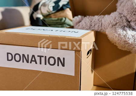 Donation boxes in living room. Packed cardboard boxes full of clothes and toys on couch. Concept of charity, social care and volunteering Donation boxes in living room. Packed cardboard boxes full of clothes and toys on couch. Concept of charity, social care and volunteering 124775538