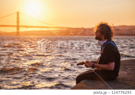 Street musician playing electric guitar in the street 124776295