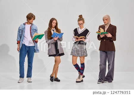 Group portrait of young people, girls and boy, different nations, dressed trendy casual outfits, reading literature against grey background. Group portrait of young people, girls and boy, different nations, dressed trendy casual outfits, reading literature against grey background. 124776351
