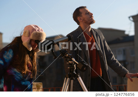 Instructor looks upward while student peers into solar telescope Instructor looks upward while student peers into solar telescope 124776856
