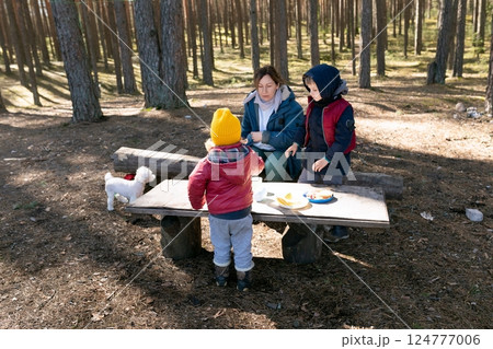 Family enjoys picnic in peaceful forest with children and small dog during sunny day Family enjoys picnic in peaceful forest with children and small dog during sunny day 124777006