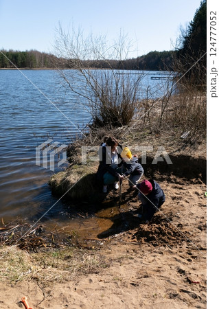 Children exploring a riverbank on a sunny spring day while engaging in playful activities near the 124777052
