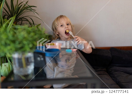 Child enjoying snacks at home in a cozy living room during the afternoon Child enjoying snacks at home in a cozy living room during the afternoon 124777141