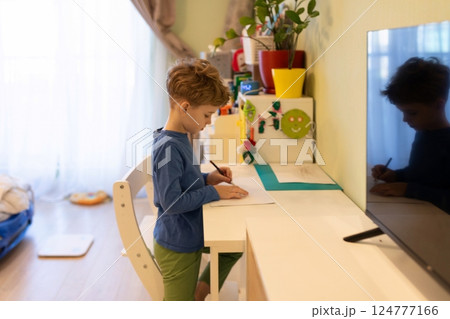 Young child engaged in creative drawing activity at a bright and colorful desk in a cozy room Young child engaged in creative drawing activity at a bright and colorful desk in a cozy room 124777166