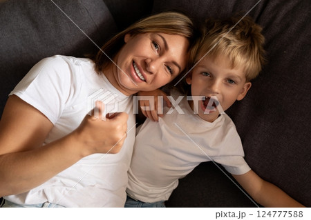 Mother and son sharing a joyful moment while lounging on the couch at home in the afternoon Mother and son sharing a joyful moment while lounging on the couch at home in the afternoon 124777588