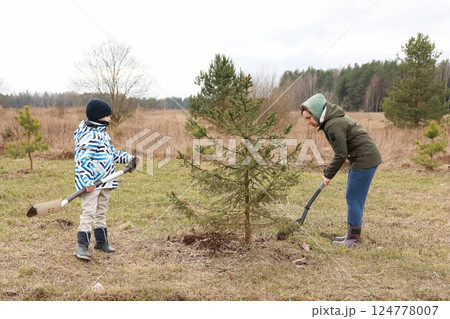Children planting a tree in a rural area during early spring, embracing nature and environmental 124778007