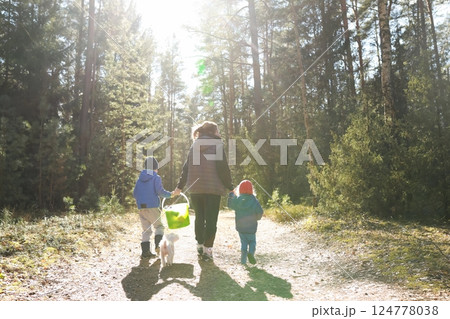 Family enjoys a sunny day walking in the forest with a dog and a basket in the late afternoon Family enjoys a sunny day walking in the forest with a dog and a basket in the late afternoon 124778038