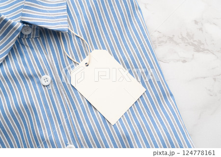 Blue striped shirt with blank tag label on marble background. Mock up for design. 124778161
