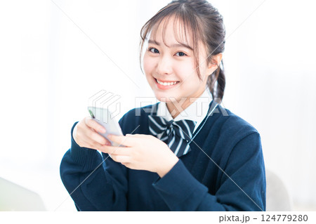 スマホを握りしめて微笑む女子高生 スマホを握りしめて微笑む女子高生 124779280