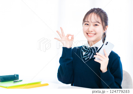 スマホを握りしめてポーズをとる女子高生 124779283