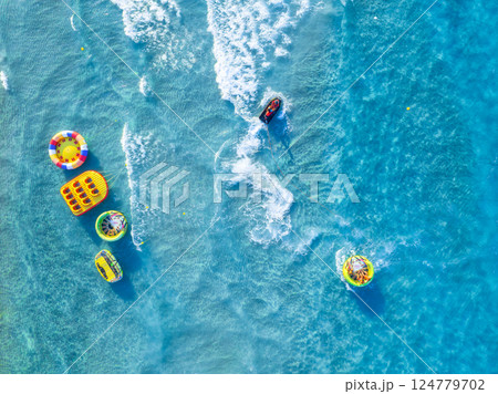 People having fun on the beach. Active recreation. Aerial view on fast boat on blue sea. 124779702