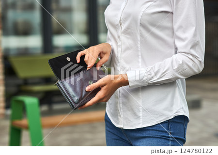 Woman holding wallet, casual attire, unrecognizable, outdoor setting, blue jeans, white shirt, modern lifestyle concept Woman holding wallet, casual attire, unrecognizable, outdoor setting, blue jeans, white shirt, modern lifestyle concept 124780122