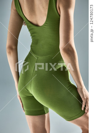 Woman in form-fitting green bodysuit showing back and arms, emphasizing posture and athletic clothing concept Woman in form-fitting green bodysuit showing back and arms, emphasizing posture and athletic clothing concept 124780173