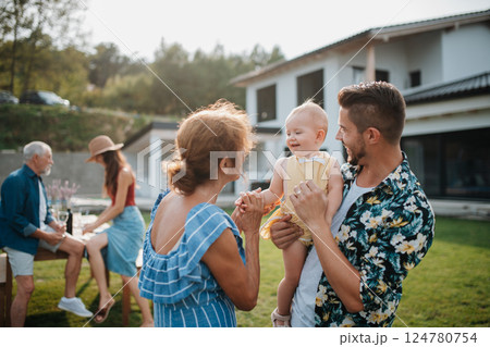 Parents welcoming their son, daughter-in-law, and baby at a family barbecue. 124780754