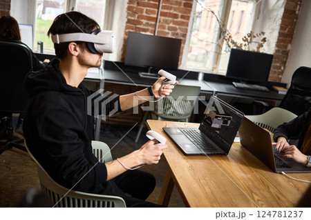Man using virtual reality headset with controllers in modern office, technology and innovation in work environment concept 124781237