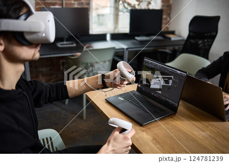 Man using virtual reality headset with controllers in modern office environment for immersive experience concept Man using virtual reality headset with controllers in modern office environment for immersive experience concept 124781239