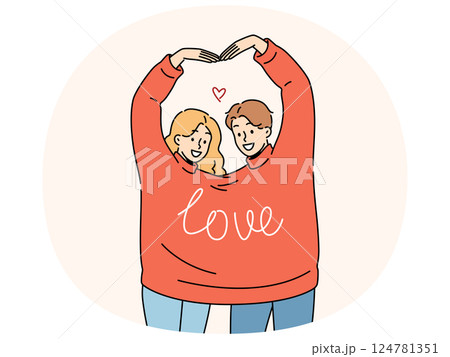 Couple in love wearing same sweater together makes heart shape from hands in sympathy sign Couple in love wearing same sweater together makes heart shape from hands in sympathy sign 124781351