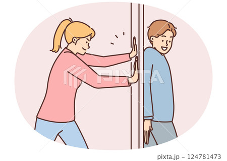 Positive man hides behind door preventing girlfriend from passing or arranging prank 124781473
