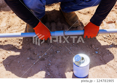 Contractor in gloves connects two electrical plastic pipes on construction site with during foundation work 124781905