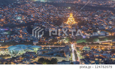 Illuminated Tsminda Sameba Cathedral or Holy Trinity Cathedral of Tbilisi and Public Service Hall aerial day to night timelapse Georgia 124782079