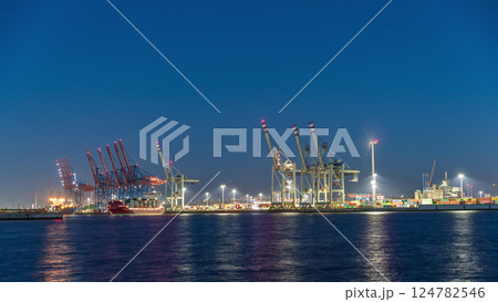 Night timelapse of Hamburg cargo port, showcasing container terminals, cranes and cargo ships on the Elbe River. Night timelapse of Hamburg cargo port, showcasing container terminals, cranes and cargo ships on the Elbe River. 124782546
