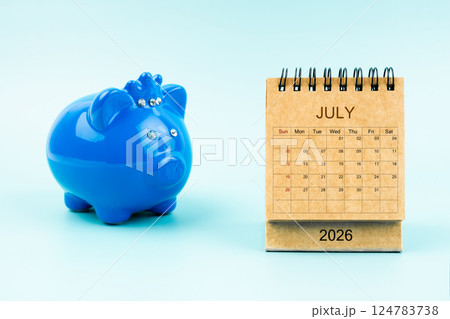 Blue piggy bank and blank July 2026 calendar, Reminder schedule of savings money. Blue piggy bank and blank July 2026 calendar, Reminder schedule of savings money. 124783738