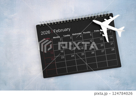 February 2026 black calendar and airplane toy on wooden table. 124784026