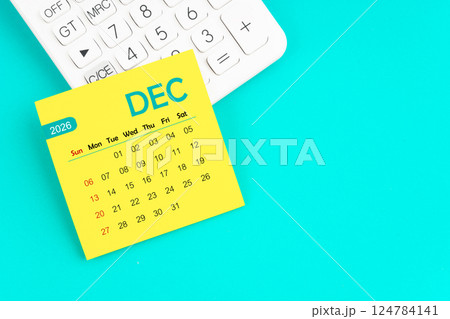 December 2026 calendar page with calculator on blue background. 124784141