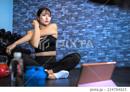 タブレットでYouTube動画を見ながらジムで運動するかっこいい女性 ストレッチ やり方 動画視聴 タブレットでYouTube動画を見ながらジムで運動するかっこいい女性 ストレッチ やり方 動画視聴 124784825