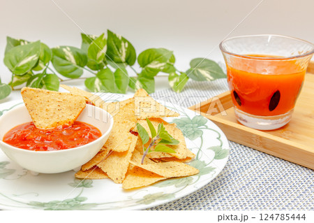 トウモロコシからできているトルティーヤチップスとサルサソースと野菜ジュース トウモロコシからできているトルティーヤチップスとサルサソースと野菜ジュース 124785444